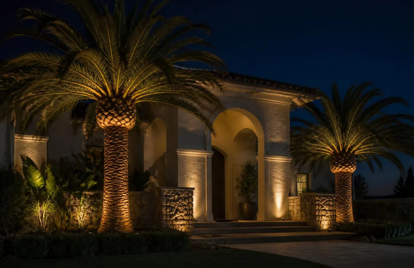 Orange County home facade lit with warm landscape lighting at night