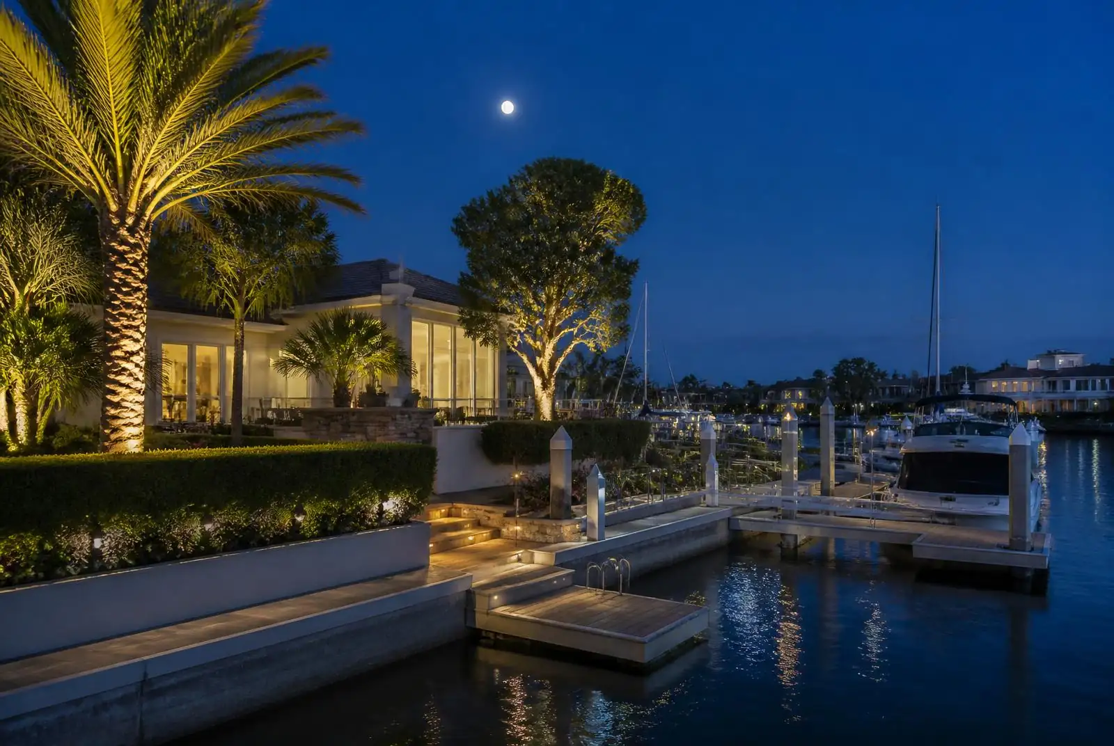 Newport Beach waterfront home with a lit private dock at dusk